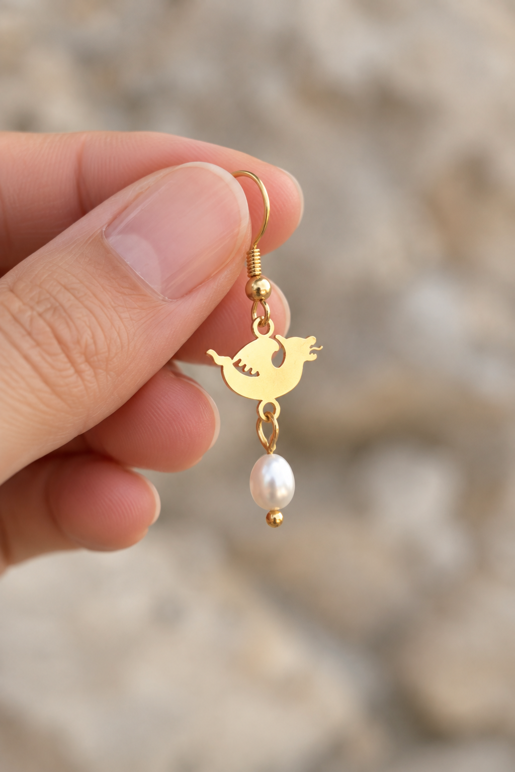 Dragon & Pearl Gold earring held in hand